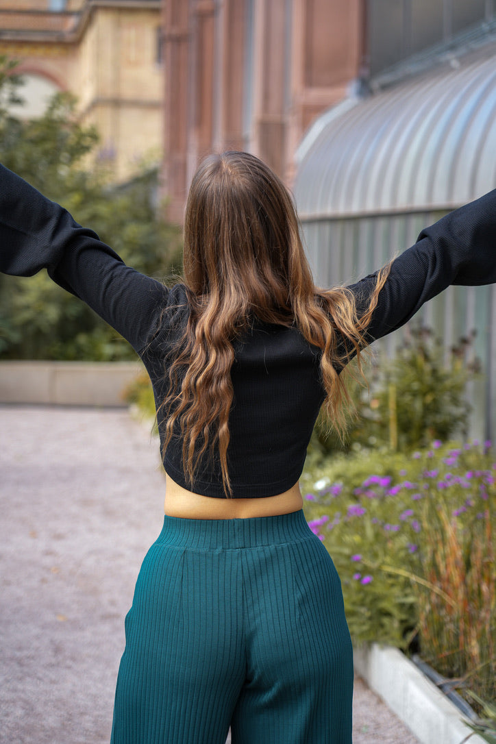 Zeitloser Damenpulli in tiefem Schwarz, mit Trompetenärmeln und nachhaltigem Material.