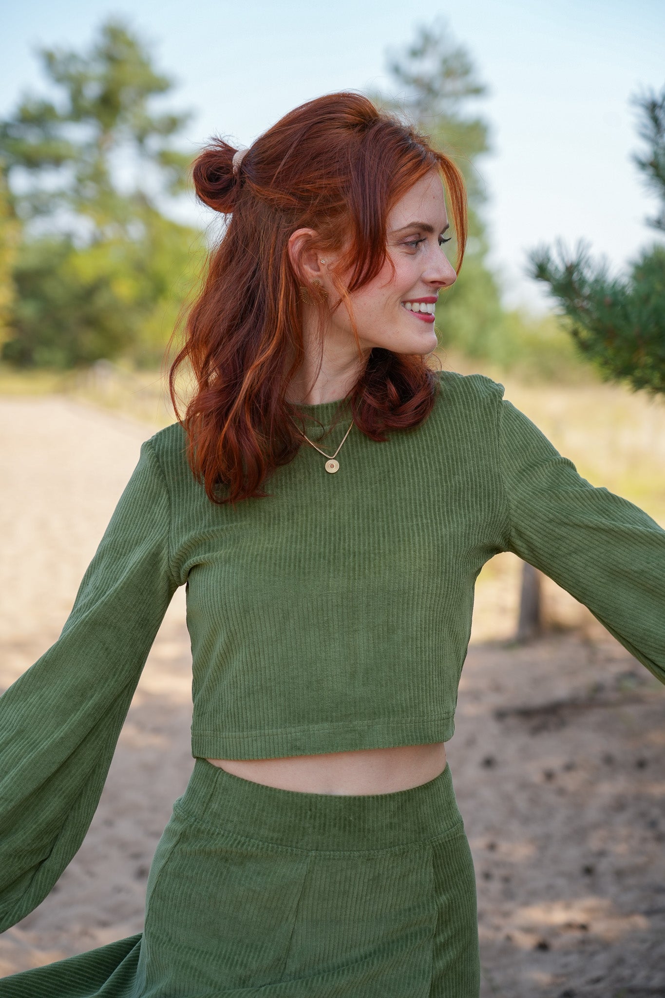 Elegant geschnittener Crop-Pullover in feinem Olive, mit femininen Ballonärmeln und 100 % GOTS-zertifiziertem Cord.