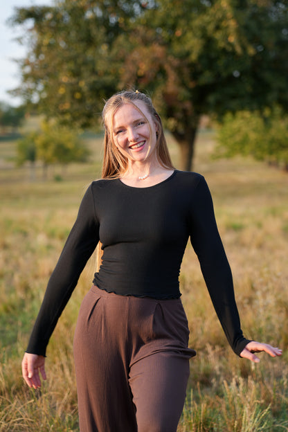 Trendiger nachhaltiger Damen Longsleeve in Schwarz mit längerem Schnitt und verspielten Rüschen für moderne Capsule Wardrobe Outfits