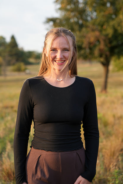 Wunderschönes figurbetontes Langarmshirt in Schwarz mit Rundhalsausschnitt und romantischem Rüschensaum für trendige Pinterest Looks