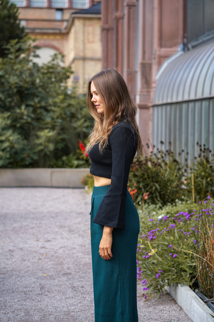 Moderner Crop Pulli in tiefem Schwarz, mit voluminösen Ärmeln und betonter Taille für einen femininen Look.